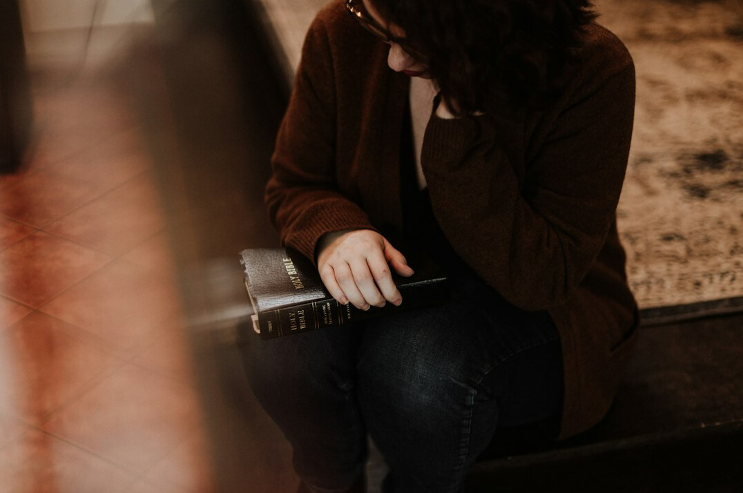 Middle-aged Latin American woman reviewing household expenses in a notebook at a kitchen table